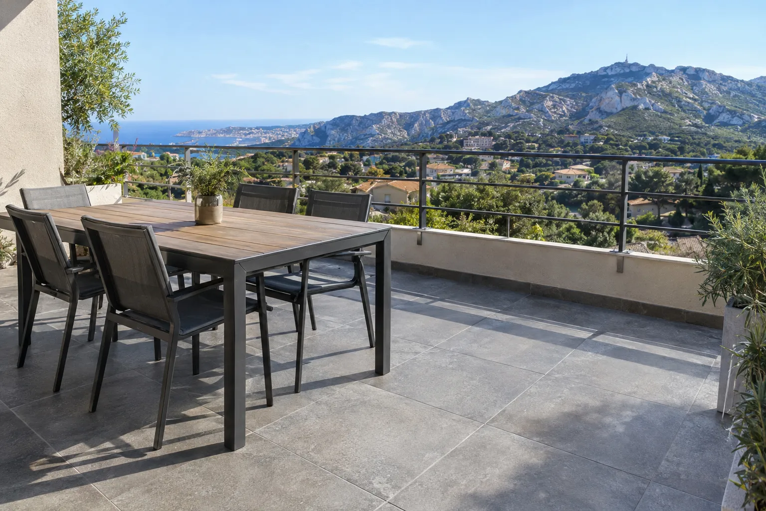 Une terrasse carrelée en grès cérame antidérapant, avec table et vue sur les collines marseillaises.